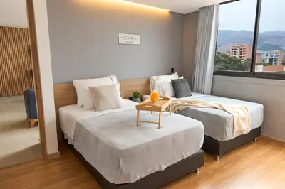 a hotel room with two beds and a window at Stadio Aparta-Suite Bliss Rosa Negra in Medellín
