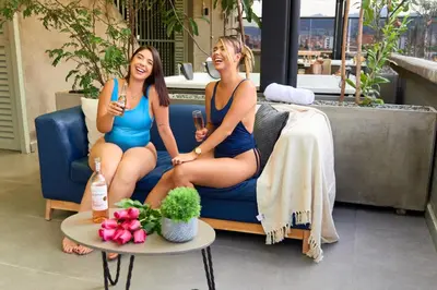 two women in bathing suits sitting on a couch at Inviting Stadio Suite Rosa Negra in Medellín