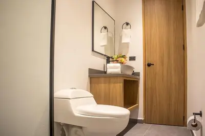 a bathroom with a white toilet and a mirror at Inviting Stadio Suite Rosa Negra in Medellín