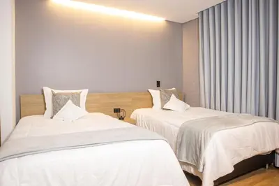 two beds in a hotel room with white sheets at Cozy Stadio Escape Rosa Negra Stay in Medellín