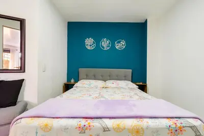 a bedroom with a bed with a blue wall at Studio apartment in La Floresta near the subway in Medellín