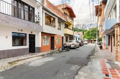 an empty city street with parked cars and buildings at Studio apartment in La Floresta near the subway in Medellín