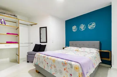 a bedroom with a bed and a blue wall at Studio apartment in La Floresta near the subway in Medellín