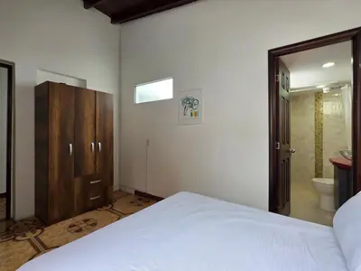 a bedroom with a white bed and a bathroom at 5StarHomes - Casa privada cerca al Estadio y la 70 in Medellín