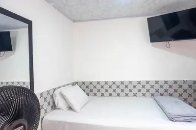 a bedroom with a white bed and a fan at Hotel Familiar in Medellín