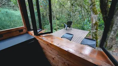 a wooden deck with a table and chairs in a forest at Cabaña Silencio in Guarne