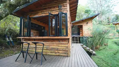 a wooden cabin with two stools on a deck at Cabaña Silencio in Guarne