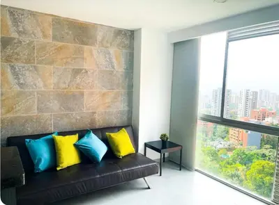 a living room with a black couch with yellow and blue pillows at Apartaestudio de 2 habitaciones cerca a provenza y el tesoro in Medellín