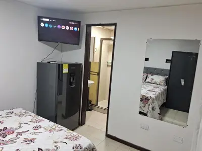 a room with a bed and a mirror and a television at Confortable Apartamento Parque Caldas Manizales in Manizales