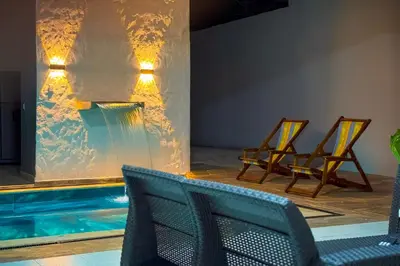 two chairs and a swimming pool with a waterfall at Casa Bella in Honda