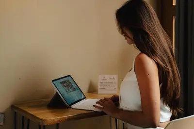 a woman in a white dress using a laptop computer at Suite con jacuzzi en El Poblado in Medellín