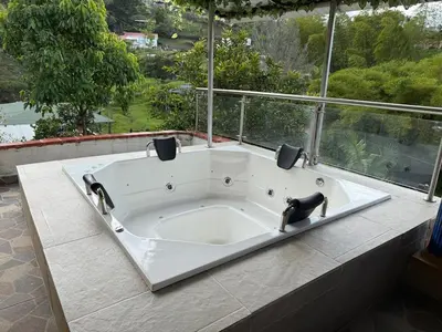 a large white bath tub sitting in front of a window at House near Marial stone and old Peñol replica in Horizonte