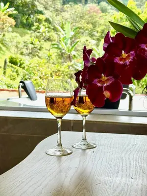 two glasses of wine sitting on a table with flowers at House near Marial stone and old Peñol replica in Horizonte