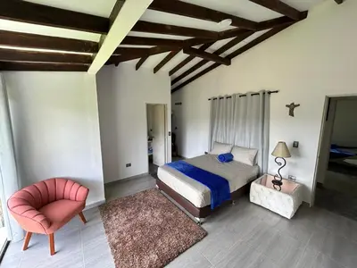 a bedroom with a bed and a chair at Espectacular vista a la represa el peñol in La Pradera