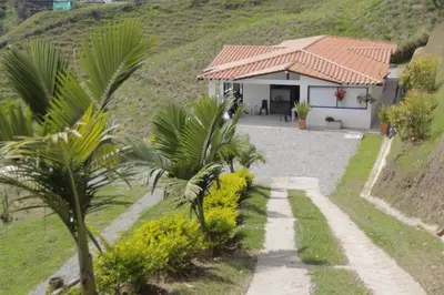 a house with a palm tree in front of it at Espectacular vista a la represa el peñol in La Pradera