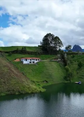a house on a hill next to a body of water at Espectacular vista a la represa el peñol in La Pradera