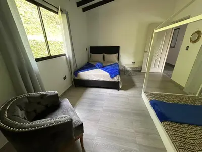 a bedroom with a bed and a chair and a mirror at Espectacular vista a la represa el peñol in La Pradera