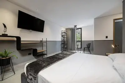a bedroom with a large white bed and a flat screen tv at Apt in el Poblado, walkable area with parking 215 in Medellín