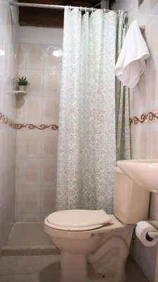 a bathroom with a toilet and a shower curtain at Las Casas de Tomate in Guatapé