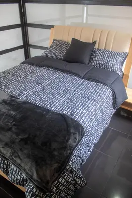 a bed with a black and white comforter and pillows at Apartment near Provence pool, gym, views and WiFi in Medellín