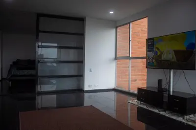 a living room with a television and a brick wall at Apartment near Provence pool, gym, views and WiFi in Medellín