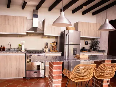 a kitchen with a counter with chairs and a refrigerator at Casa Samai Embera in Rionegro