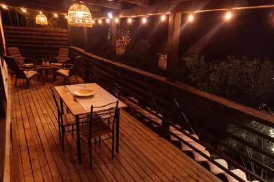 a wooden deck with tables and chairs and lights at Casa Samai Embera in Rionegro