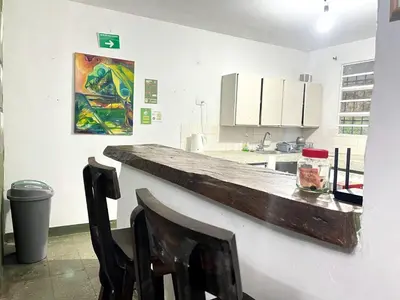 a kitchen with a counter with two chairs and a painting at Hostal Las Hamacas,Habitación #5 in Villamaría