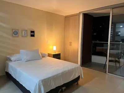 a bedroom with a bed and a sliding glass door at Apartasuite Sabaneta Vista a la ciudad parking in Sabaneta