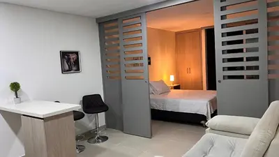 a small room with a bed and a room with a desk at Apartasuite Sabaneta Vista a la ciudad parking in Sabaneta