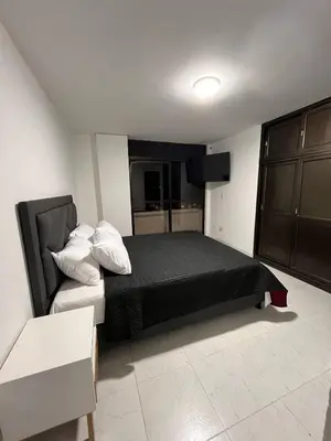 a bedroom with a bed with a black blanket and white pillows at CÓMODO APARTAMENTO CERCA De TODO EN ENVIGADO in Envigado