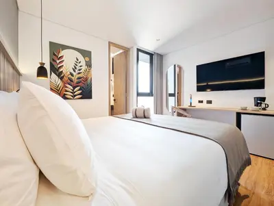 a bedroom with a white bed and a desk at Moa Select in Medellín
