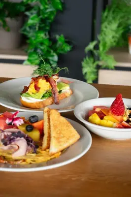 three plates of food on a wooden table at Moa Select in Medellín