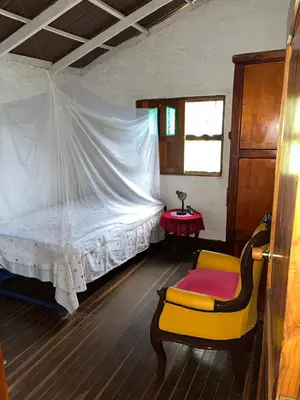 a bedroom with a white bed and a yellow chair at Finca La Tabaiba in Fredonia