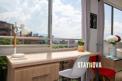 an office with a desk and a large window at Staynova loft acogedor en El Poblado, Medellín in Medellín