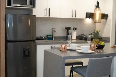 a kitchen with a stainless steel refrigerator and a table at Staynova loft acogedor en El Poblado, Medellín in Medellín