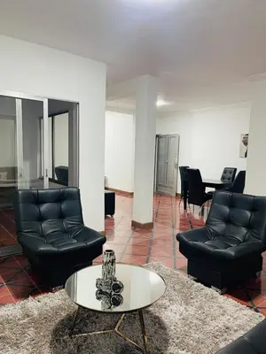a living room with black leather chairs and a table at Grandma's House in Medellín