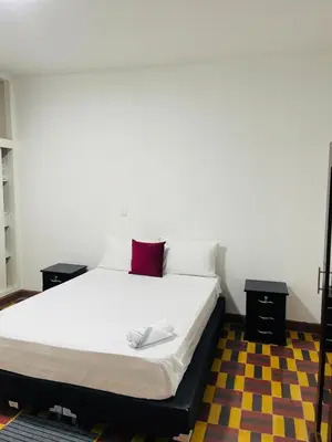 a bedroom with a white bed with a red pillow at Grandma's House in Medellín