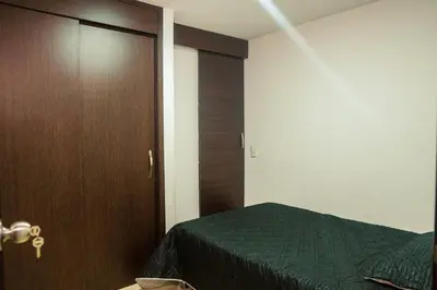 a bedroom with a bed and a wooden door at Apartamento en Sabaneta con Excelente Ubicación in Sabaneta