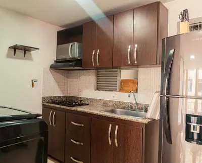 a kitchen with wooden cabinets and a stainless steel refrigerator at Apartamento en Sabaneta con Excelente Ubicación in Sabaneta