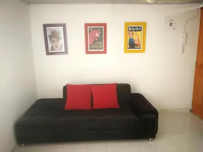 a black couch with two red pillows in a room at Acogedor Apartaestudio in Manizales