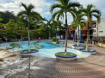 a large swimming pool with palm trees in it at Apartasol En San Jeronimo in San Jerónimo