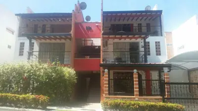 a red and white house with a black fence at Apartasol En San Jeronimo in San Jerónimo