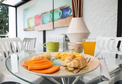 a plate of food on a glass table with orange juice at Almaviva Casa Hotel in Medellín