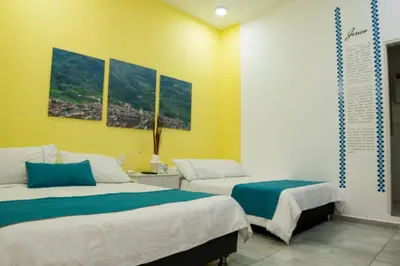 two beds in a room with yellow walls at Almaviva Casa Hotel in Medellín