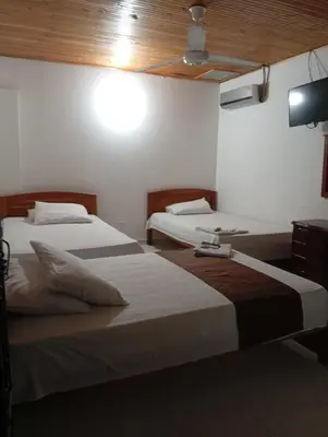 two beds in a hotel room with a tv at Hotel kerana moon in Puerto Boyacá