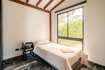 a bedroom with a bed and a desk next to a window at Nature Retreat Views, Grill, Jacuzzi & Glamping in Guarne