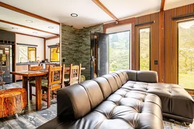 a living room with a leather couch and a table at Nature Retreat Views, Grill, Jacuzzi & Glamping in Guarne