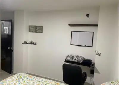 a bedroom with a bed and a white wall at Habitaciones Privadas, dentro de apartamento, cómodas y muy cercanas al Poblado in Medellín