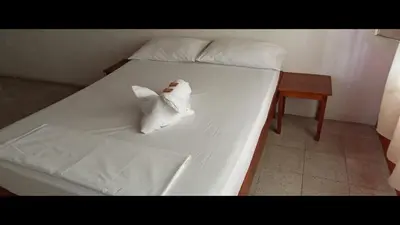 a white bed with a stuffed animal on it at Hotel San Judas in Santa Fe de Antioquia